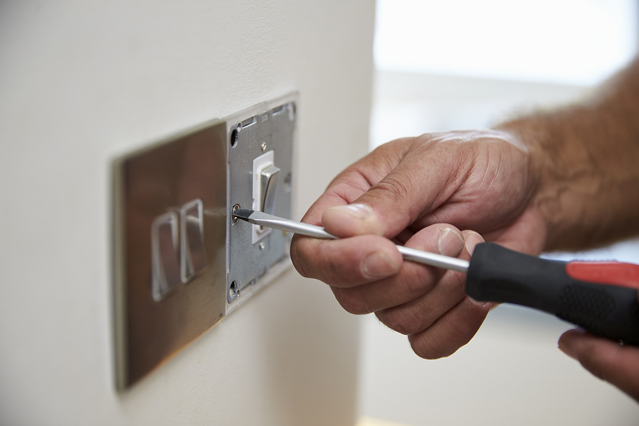 Close Up Of Electrician Repairing Domestic Light Switch